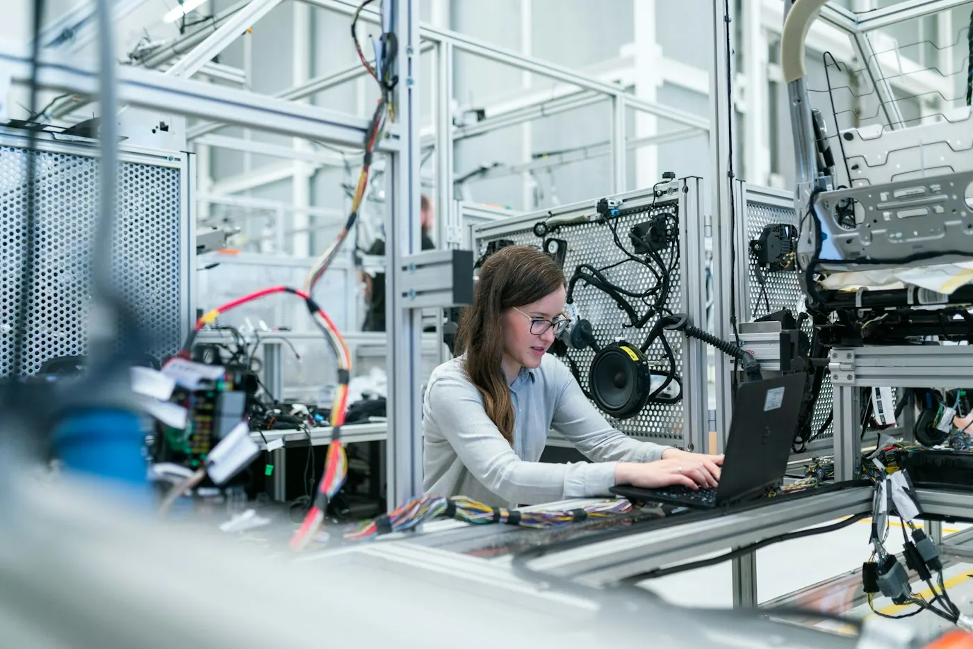 Engineer working at a laptop beside industrial equipment